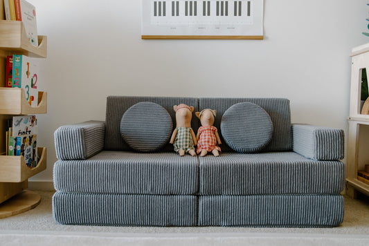 A grey corduroy Funsquare play couch in couch mode, styled with round cushions in a child’s playroom