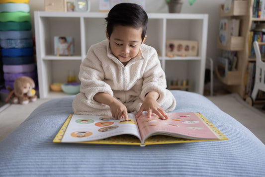 A young child reading a picture book while resting on a blue Funsquare crash pad